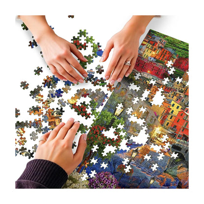 Hands assembling the RGS Cinque Terre Italy 1500 piece jigsaw puzzle on a table