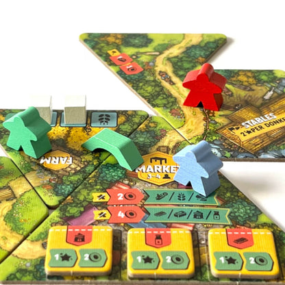Hamlet board game close-up showing villagers, donkeys, roads, market tiles and resource delivery gameplay
