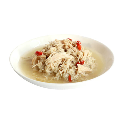 Chicken flakes and red goji berries served in broth on a white plate