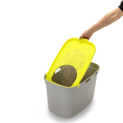 Person lifting the textured Lemon Yellow lid of a Moderna Top Cat litter box to return collected cat litter into the tray.