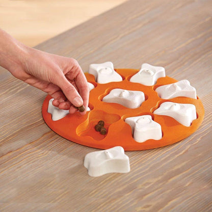Hand placing treats into Nina Ottosson Dog Smart puzzle compartments for training play