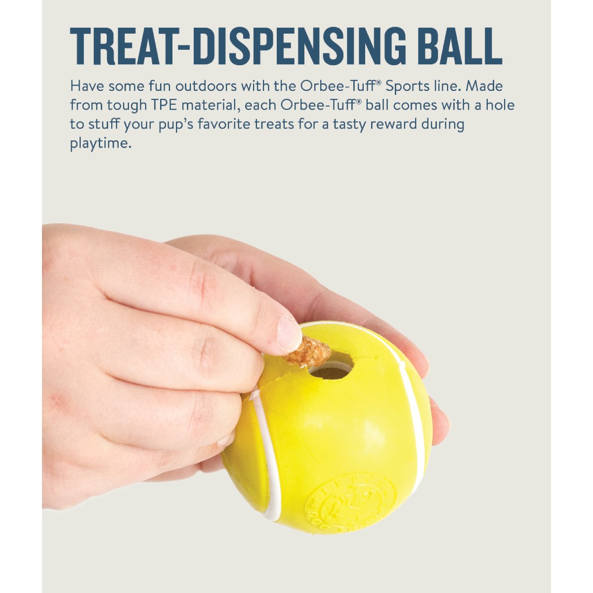 Petstages Planet Dog tennis ball treat dispenser with treat being placed into the opening for interactive play