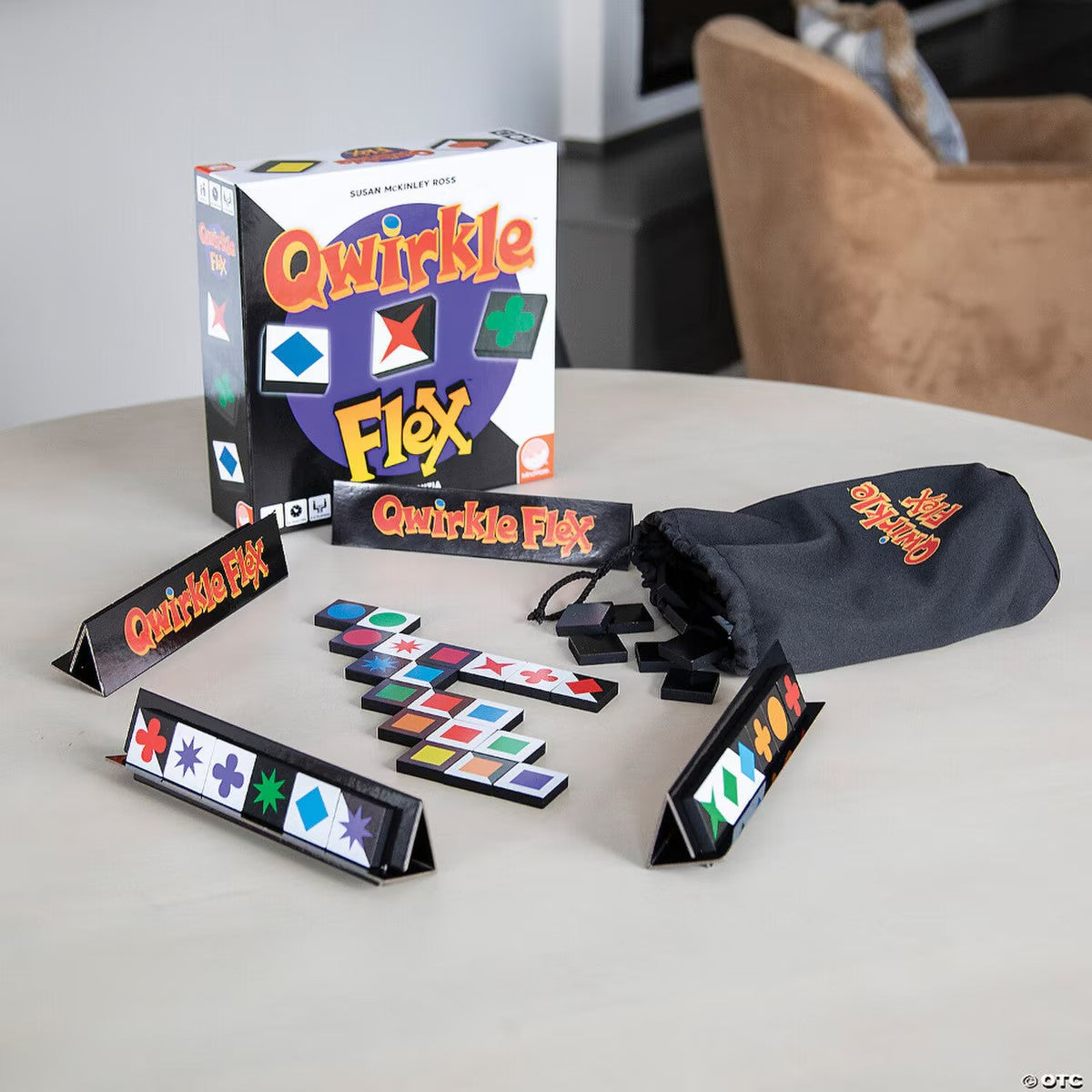 Qwirkle Flex board game set up on a table with tiles racks and bag