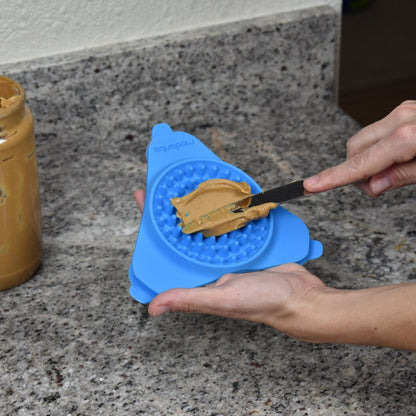 Spreadable dog treat being added to Aquapaw Slow Treater textured lick mat