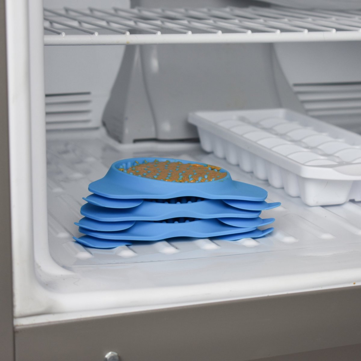 Stacked Aquapaw Slow Treater dog lick mats prepared with treats in a freezer