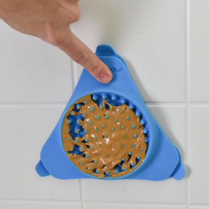 Aquapaw Slow Treater blue dog lick mat suctioned to a smooth tiled surface