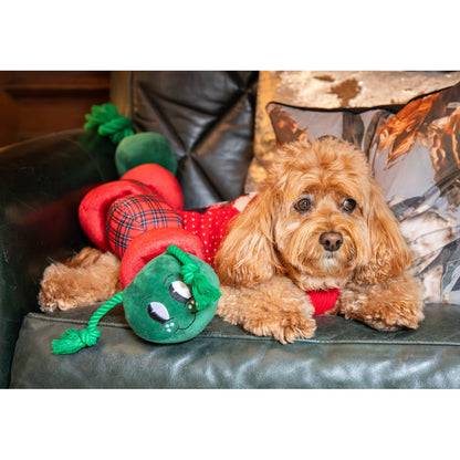 Rosewood Casper Caterpillar extra-large red and green plush dog toy resting alongside a curly-haired dog on a sofa