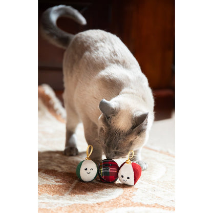 Siamese-style cat investigating three Rosewood Festive Bauble Trio Christmas cat toys on a patterned rug.