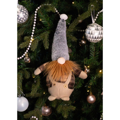 Rosewood Gerard Gonk plush dog toy nestled among Christmas tree branches decorated with silver baubles, white bead garlands and warm lights.