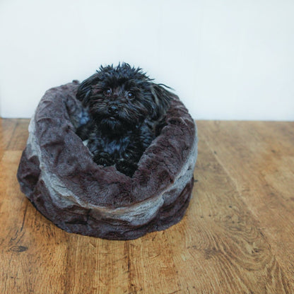 Small black dog resting inside the Rosewood Grey & Cream Snuggle Plush Round Dog Bed, surrounded by deep padded walls and soft grey patterned plush fabric.