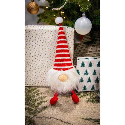 Rosewood Groopert Gonk festive plush dog toy displayed beneath a Christmas tree beside wrapped gifts, gold decorations and white baubles.