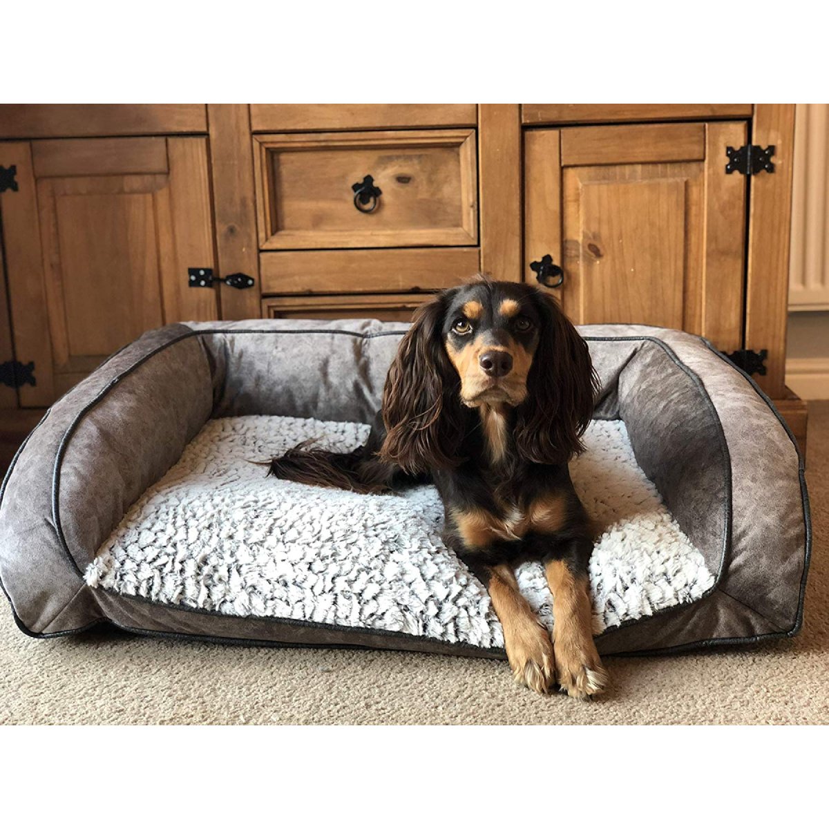 Black and tan dog resting on a grey Rosewood fleece-lined plush sofa bed with white cushion and Soft and Cosy.