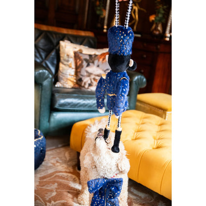Cream dog gripping the braided rope leg of Rosewood Nermal Nutcracker interactive Christmas dog toy