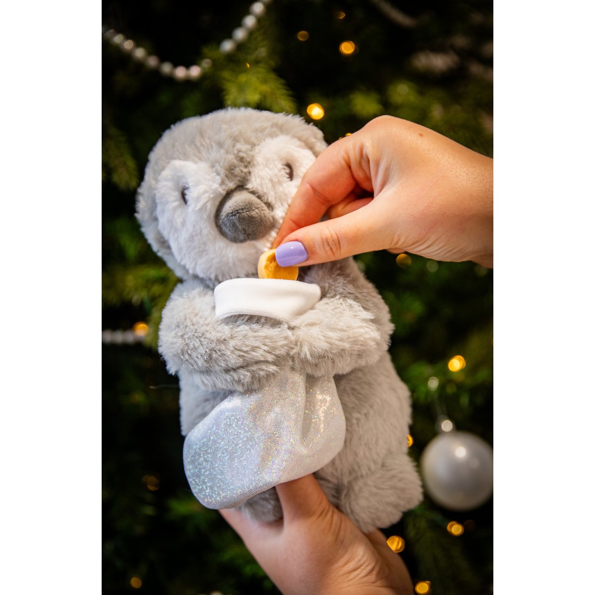 Hand placing a treat into the white stocking of Rosewood Prancer Penguin interactive plush dog toy.