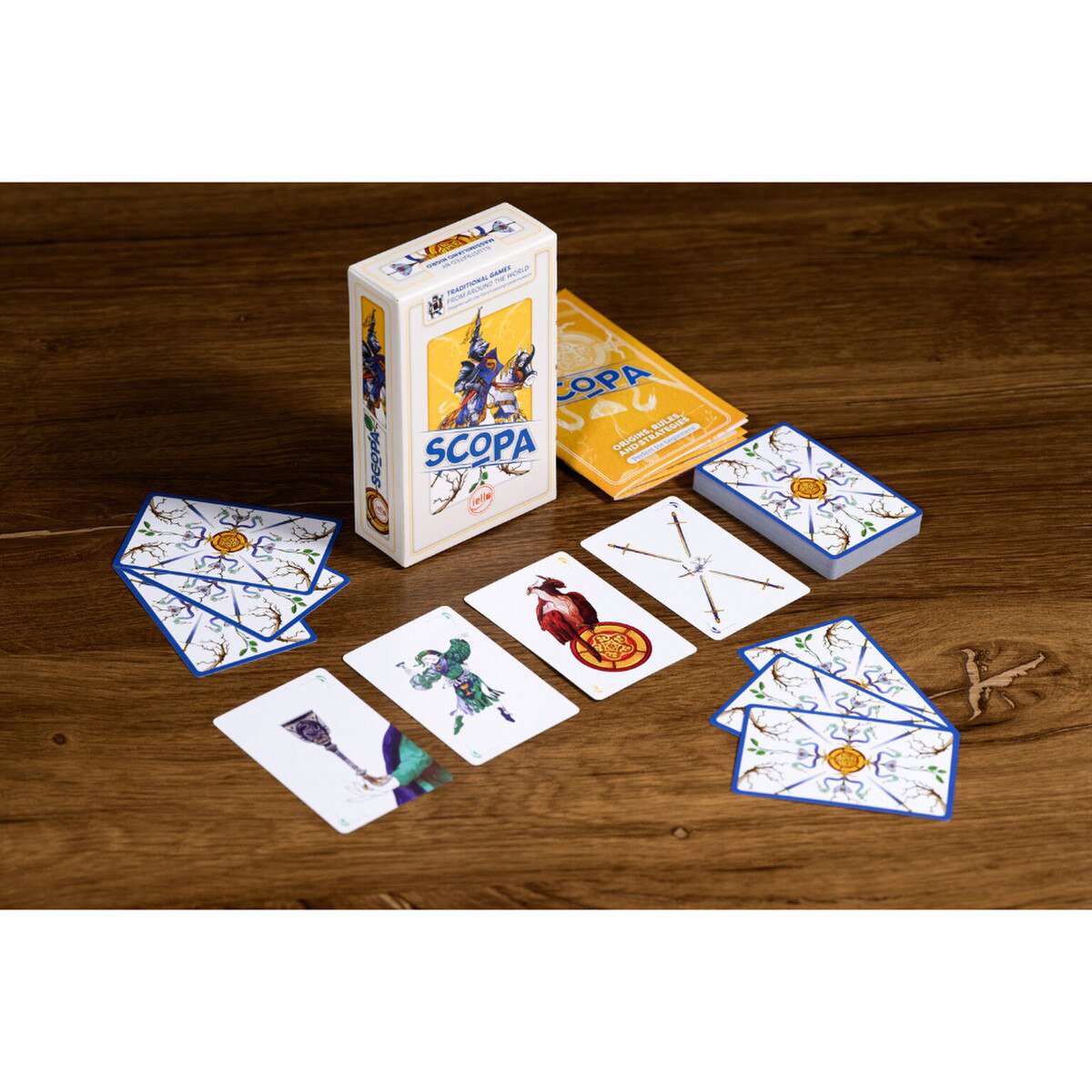 Scopa card game table setup showing illustrated cards, box and rulebook on a wooden table