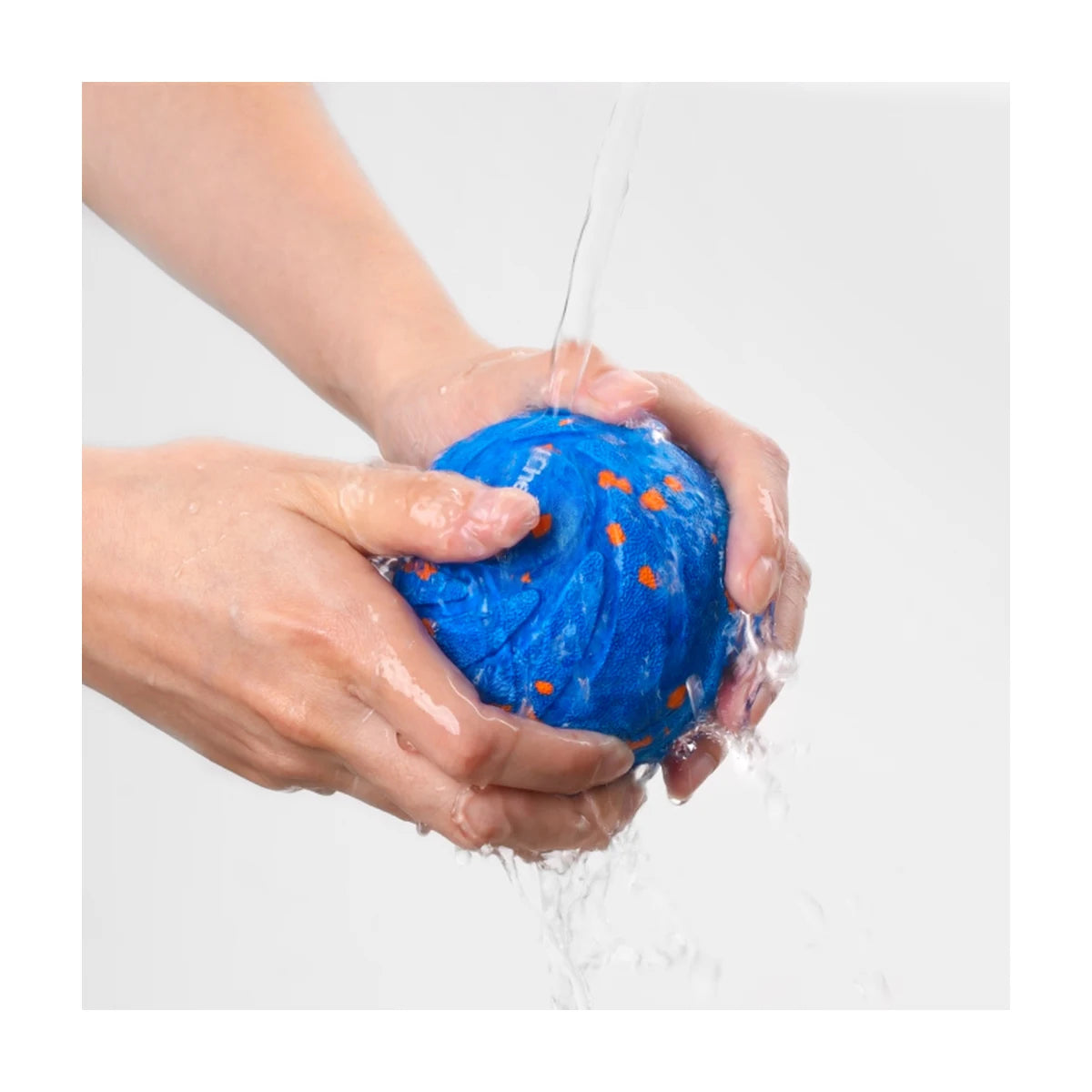 Blue interactive dog ball being rinsed under running water to clean the waterproof outer shell